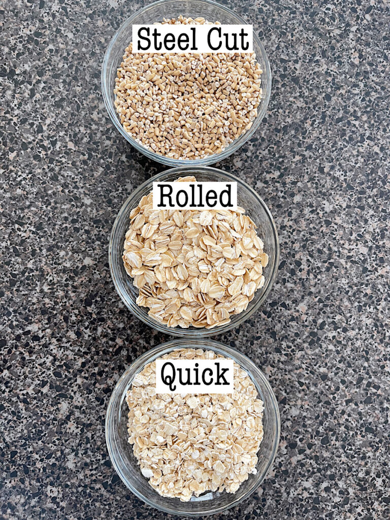 Three bowls one containing steel cut oats, one with rolled oats, and one with quick oats.