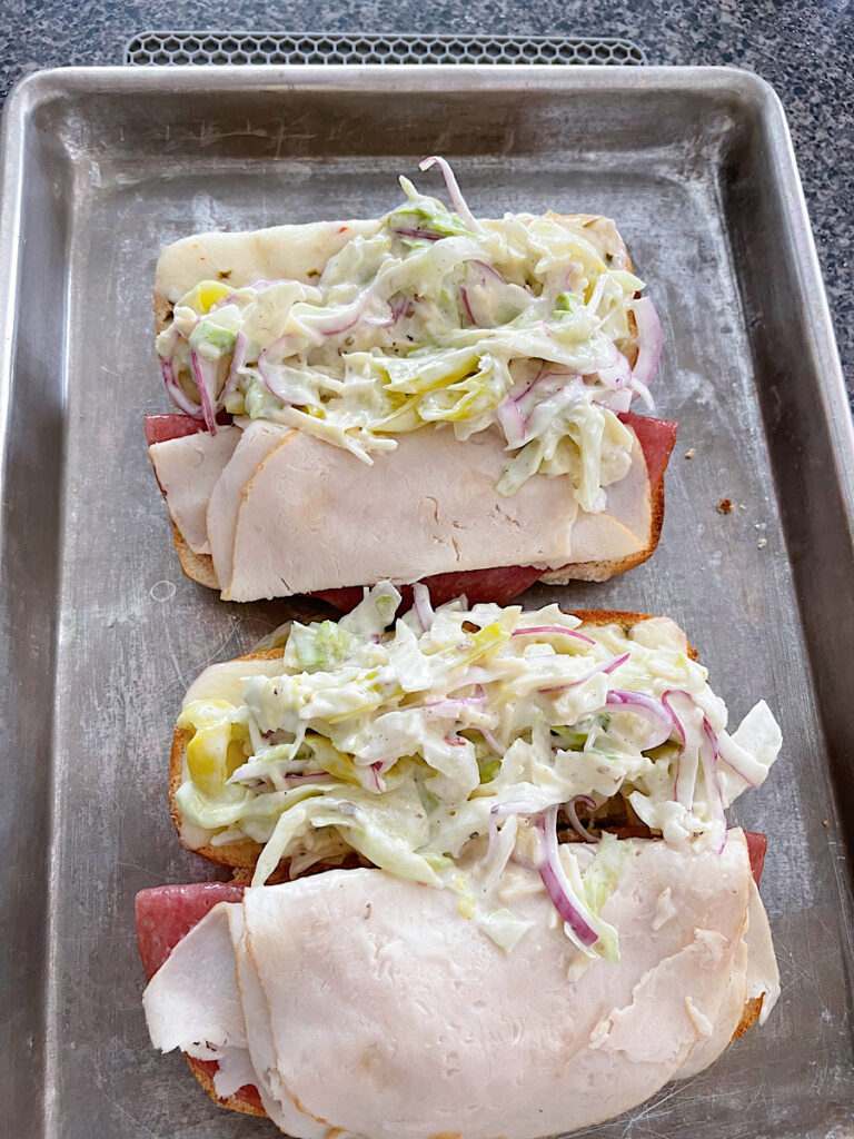 A toasted sandwich topped with tiktok grinder salad.