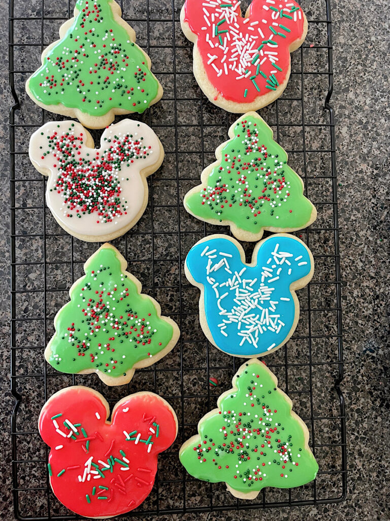 Eight Christmas sugar cookies with smooth icing and sprinkles.