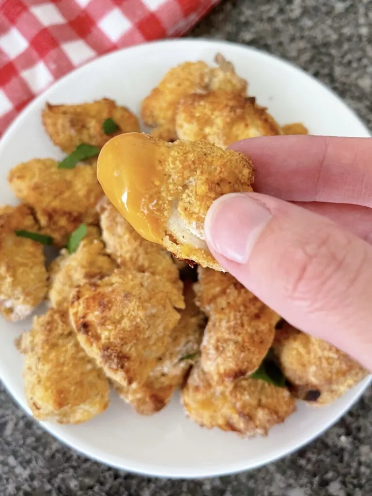 An air fryer chicken nugget with sauce.