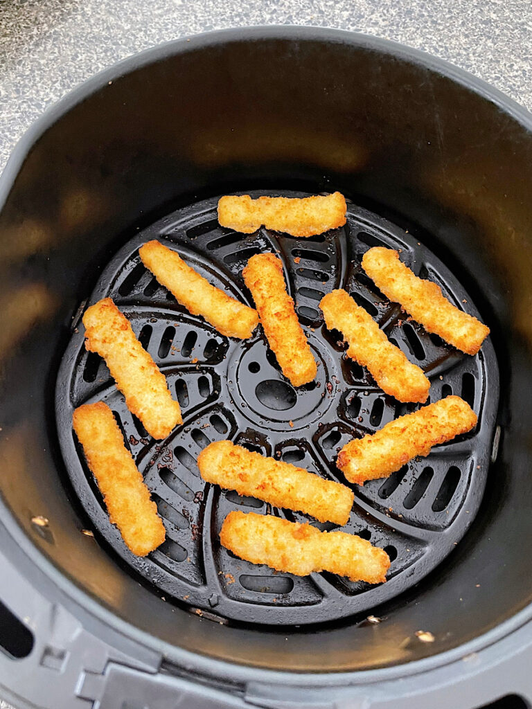 Frozen fish sticks cooked in an air fryer.