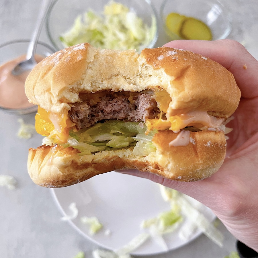 A hamburger with cheese, lettuce, and pickles that was cooked in an air fryer.