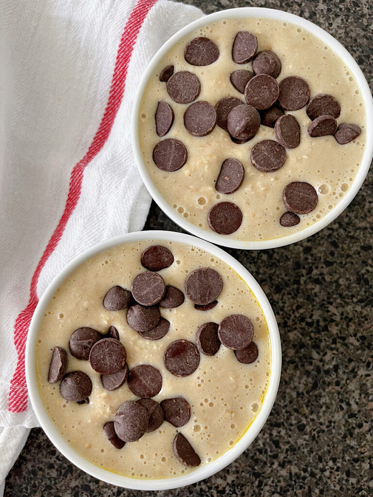 Two ramkeins with baked oats batter topped with chocolate chips.