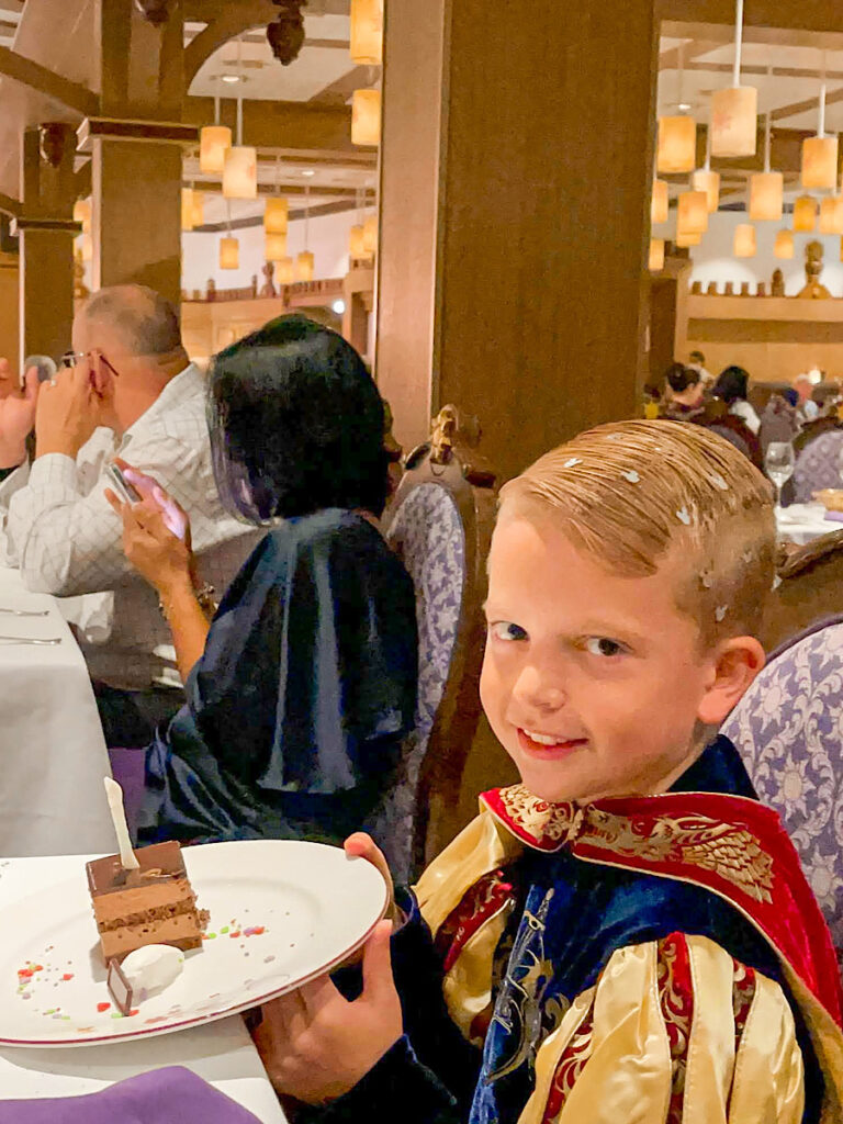 A boy with a birthday cake at Rapunzel's Royal Table on the Disney Magic.