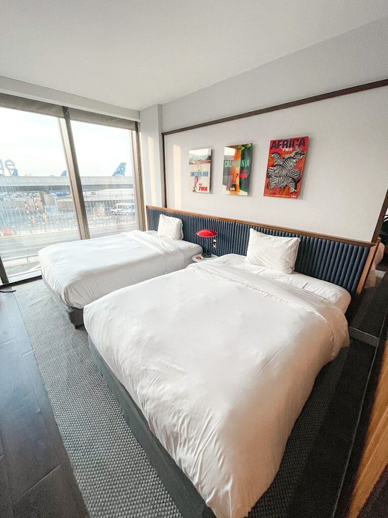 TWA Hotel room with 2 Queen beds and only one pillow per bed.