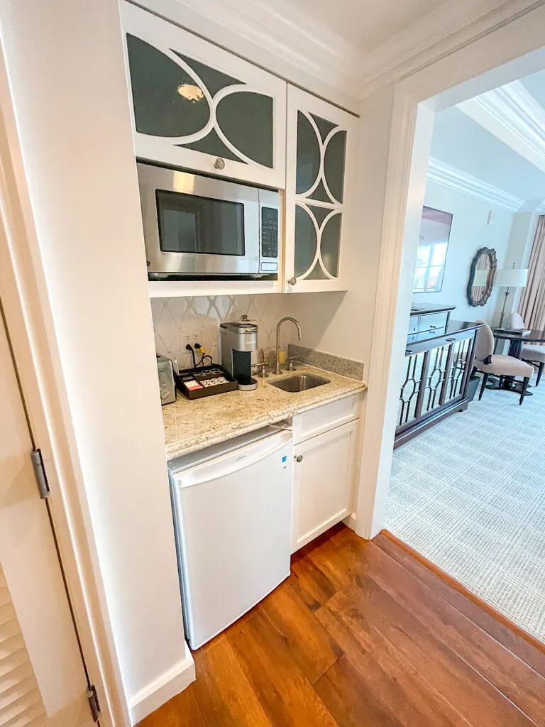 A hotel kitchenette area with a microwave, small refrigerator, coffee maker, sink, and toaster.