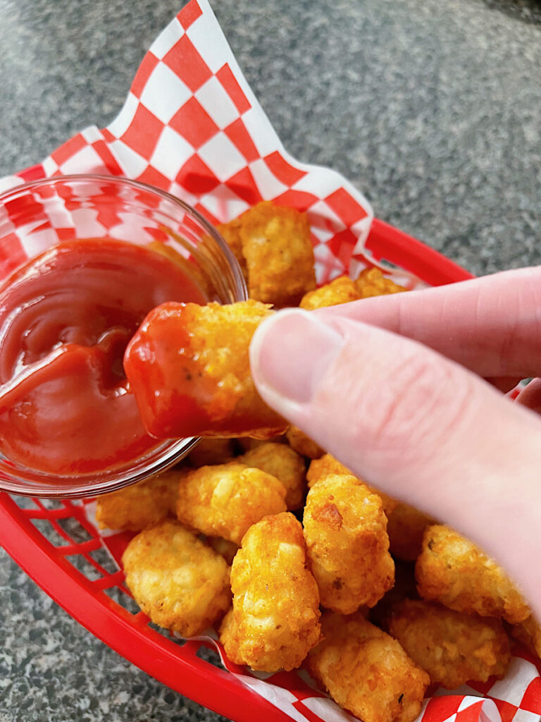 Air Fryer tater tots in a red basket with ketchup.