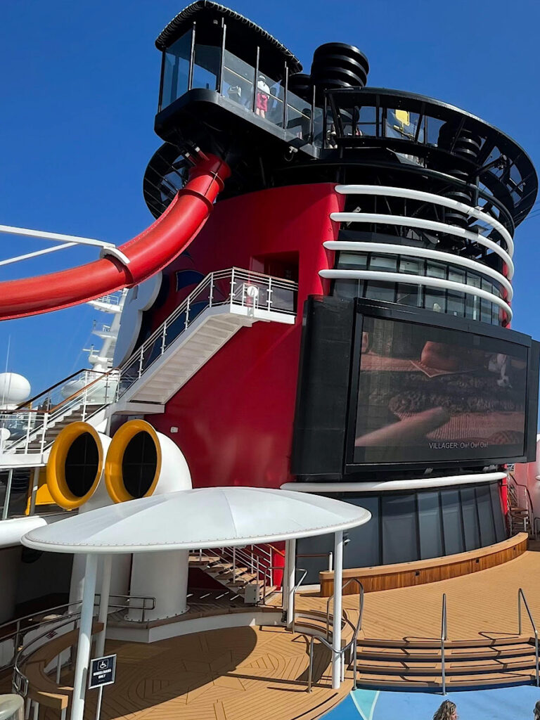 A water slide coming from the side of the funnel on the Disney Magic.