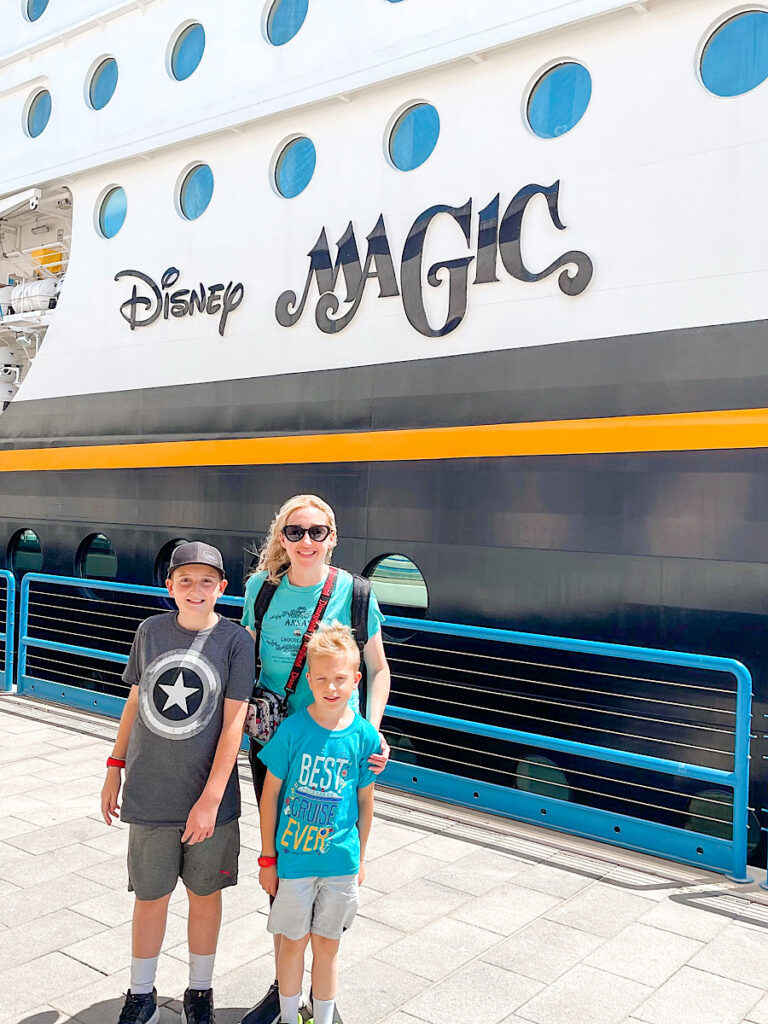 A mom and two kids in front of the Disney Magic cruise ship.
