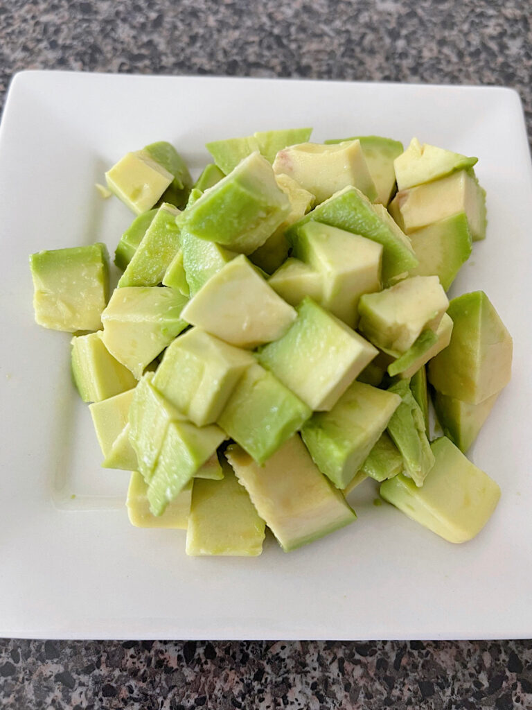 Diced avocados on a white plate.