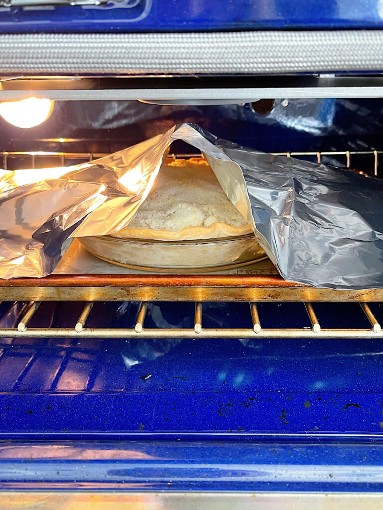 A Dutch apple pie covered loosely with foil in the oven.