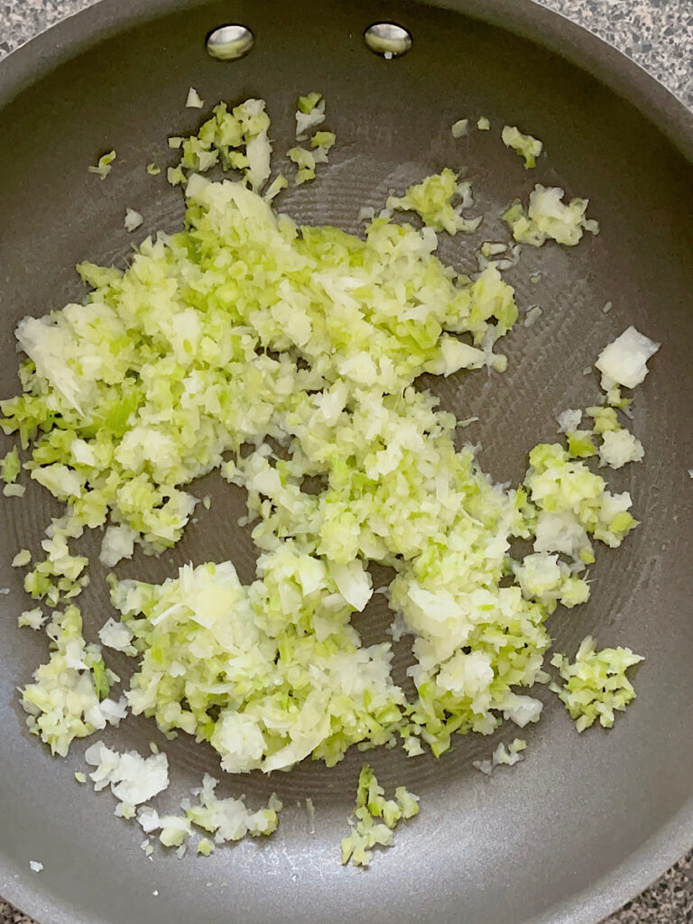Chopped onions and celery in a pan.