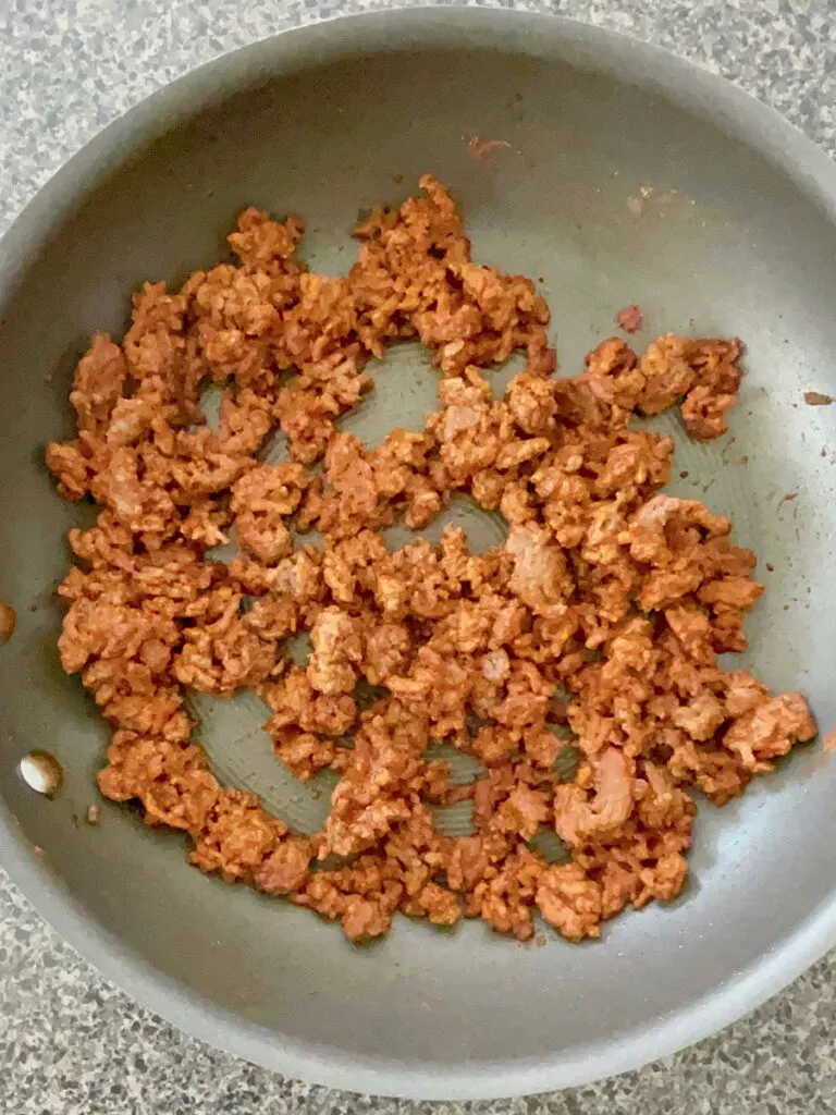Ground beef with tomato sauce and taco seasoning in a nonstick skillet.