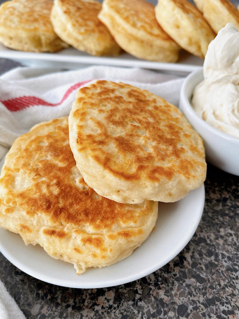 Two drop scones on a white plate next to a dish of whipped honey butter.