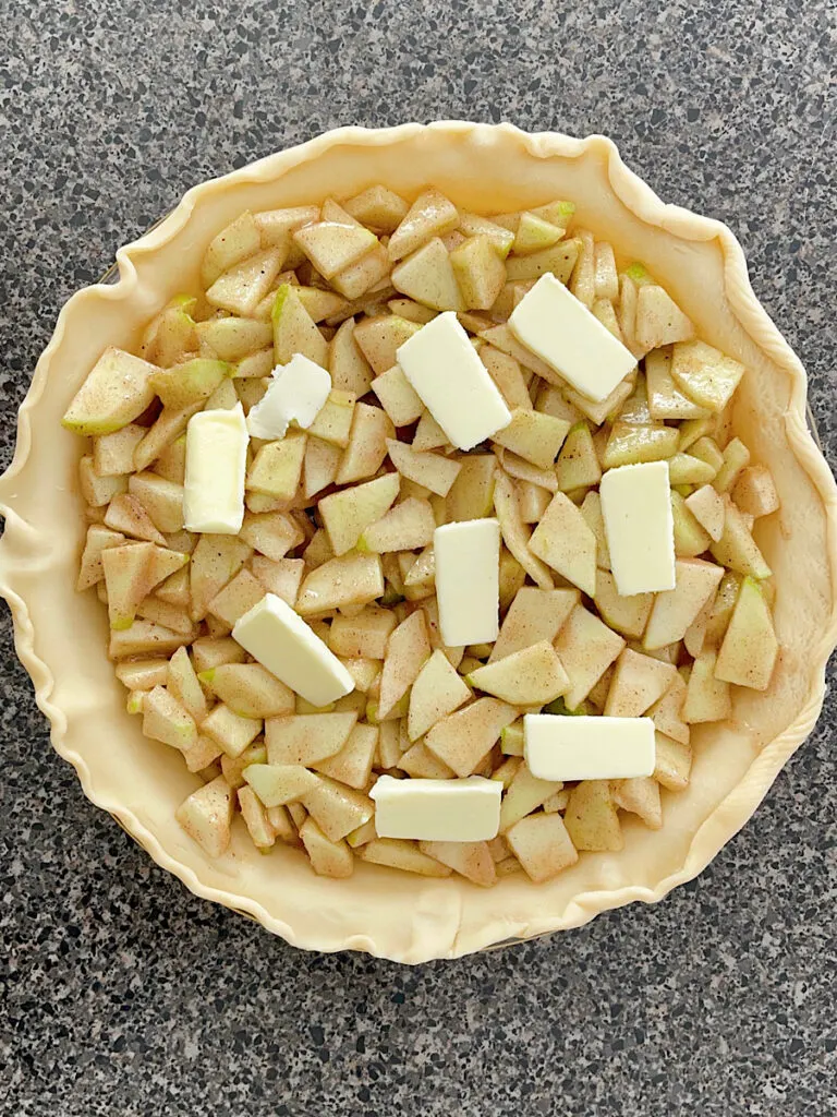 Slices of butter on apple pie filling.