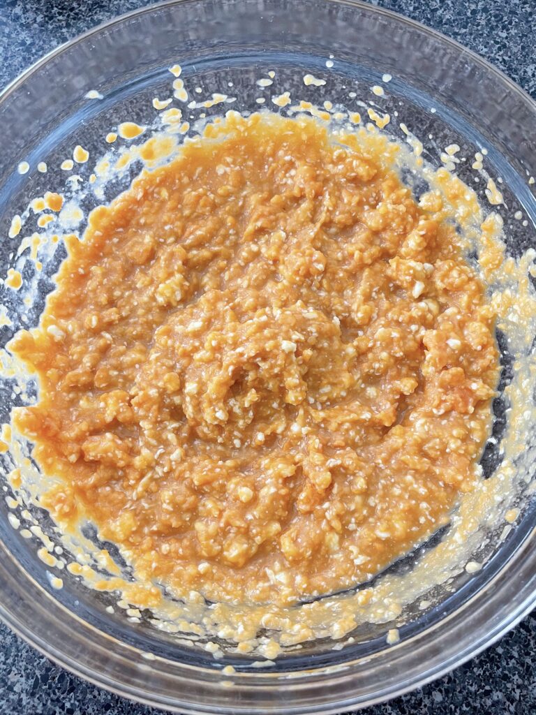 Mashed yams mixed with sugar, butter, eggs, and milk in a mixing bowl.