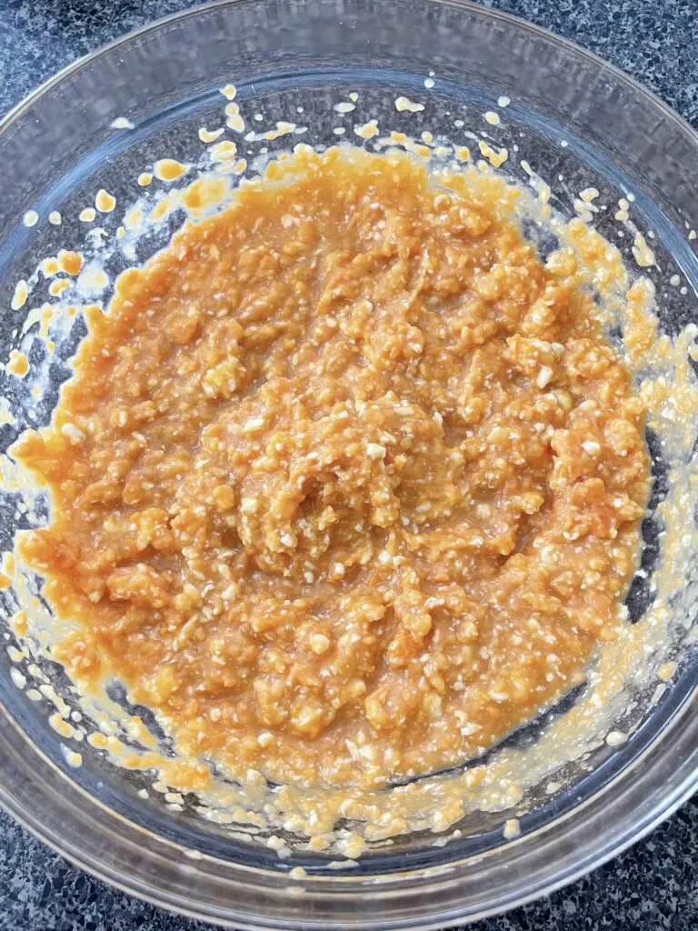 Mashed yams mixed with sugar, butter, eggs, and milk in a mixing bowl.
