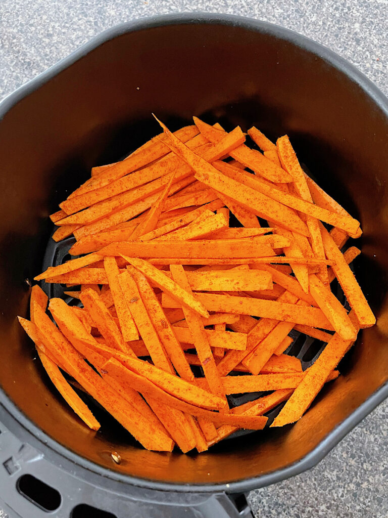 Sweet potato fries in an air fryer basket.