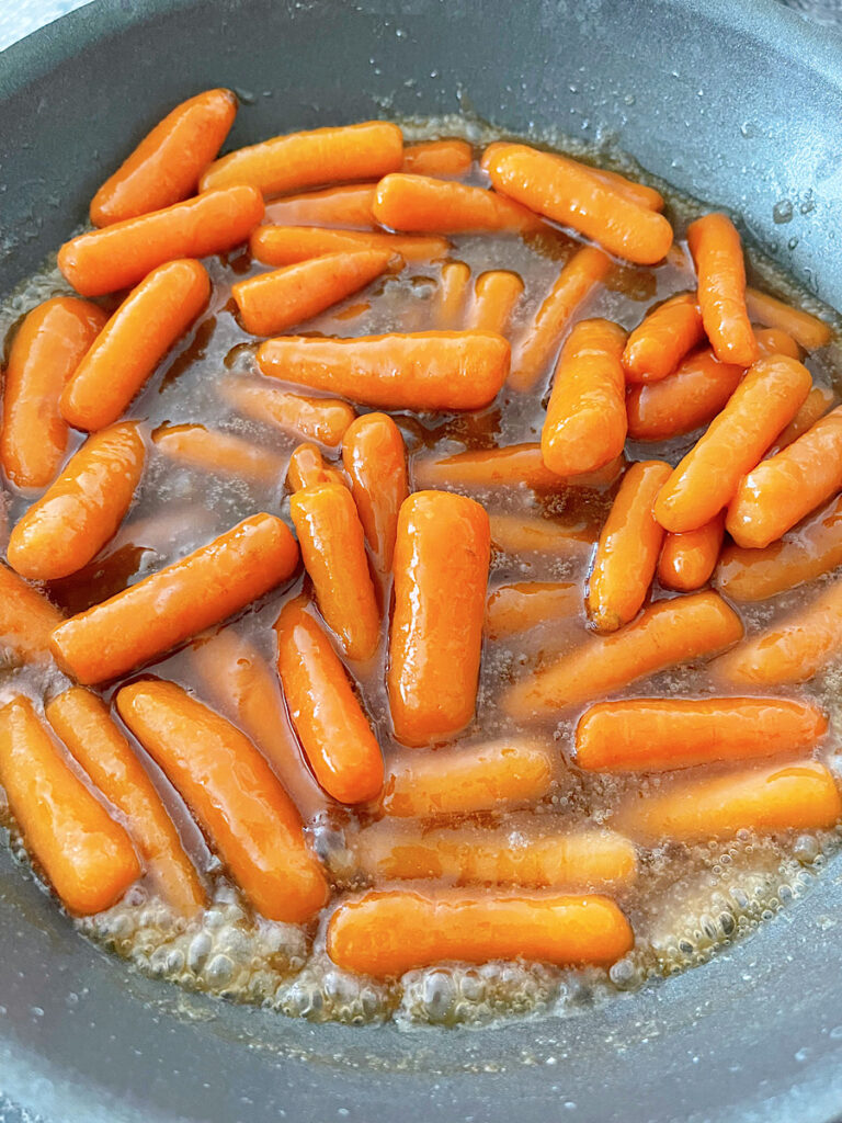 Carrots in a pan of melted butter and brown sugar.