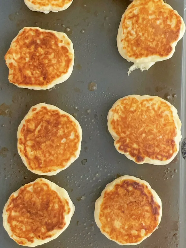 Drop scones cooking on a hot griddle.