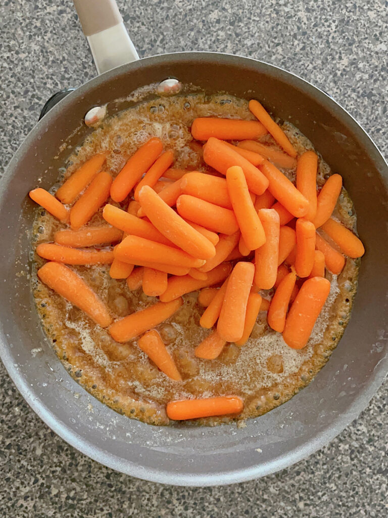 Carrots in a pan of melted butter and brown sugar.