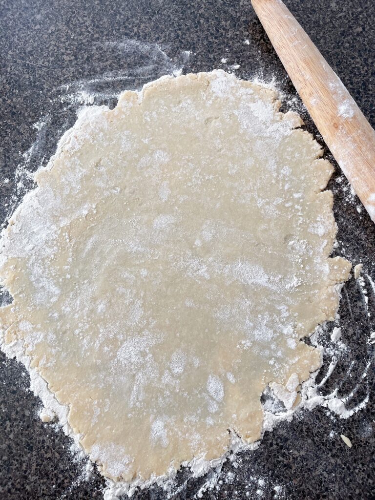 Unbaked pie crust rolled out with rolling pin.