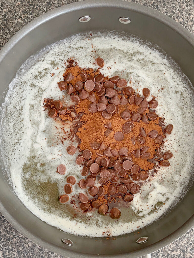 Melted butter with cocoa powder and chocolate chips in a pan.