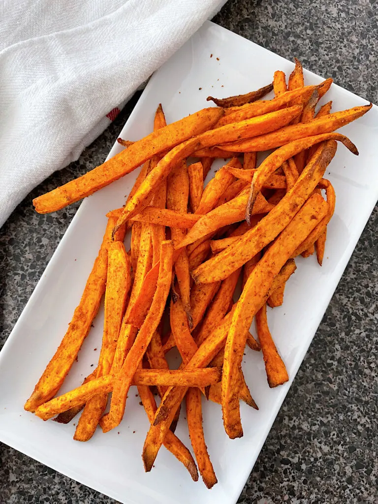 Sweet potato fries on a white plate with fry sauce.
