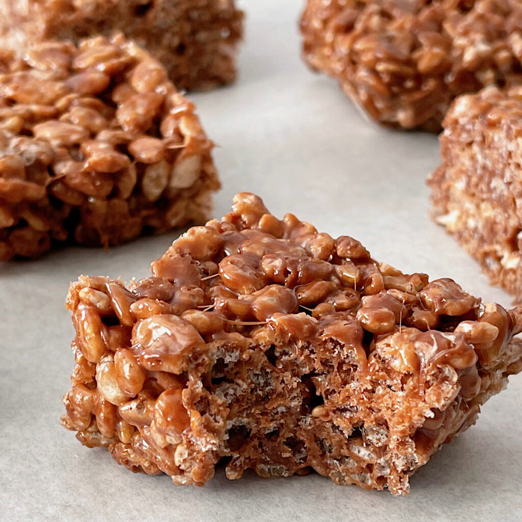 A chocolate rice crispy missing a bite.