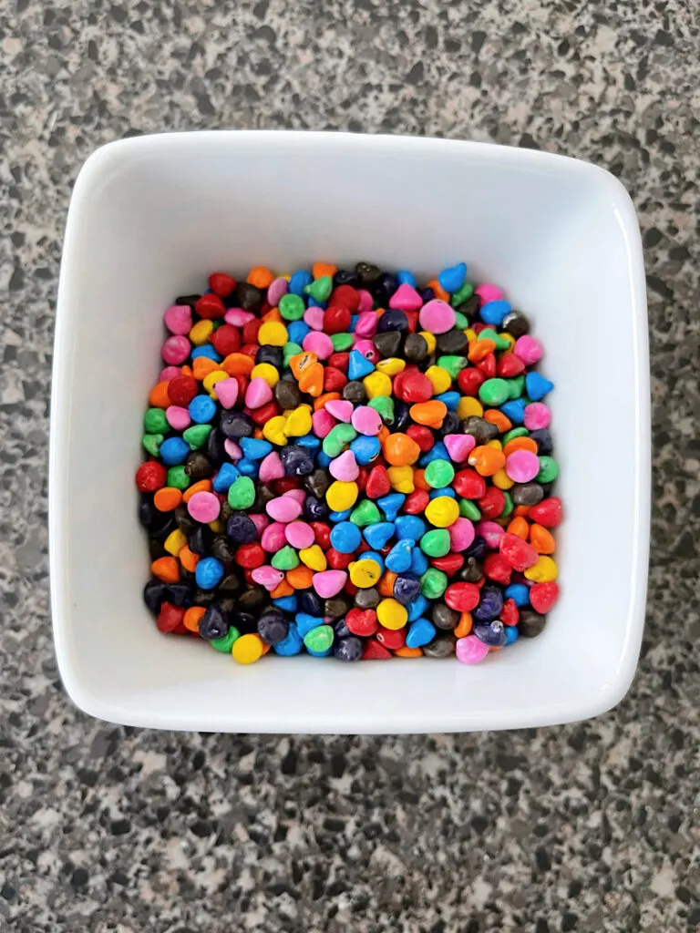 A white bowl filled with rainbow chips to make tiktok cosmic brownies.