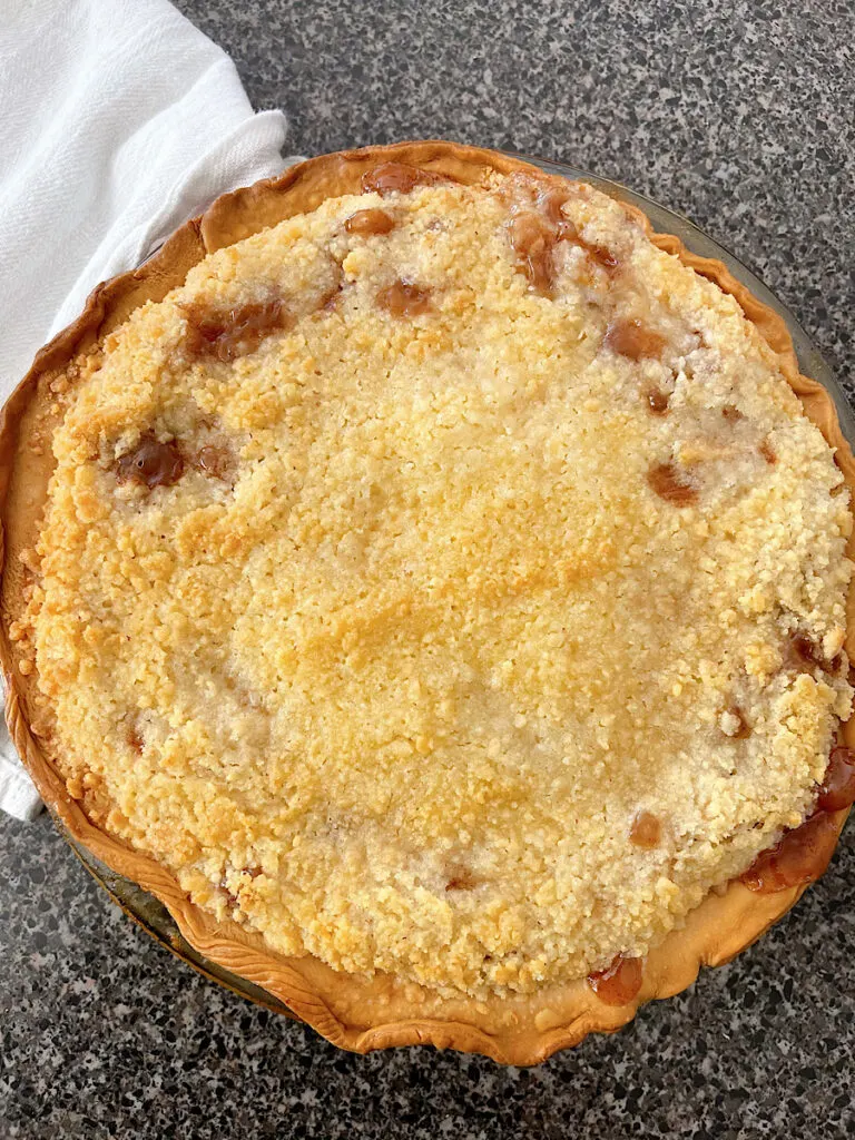 An apple pie with a golden brown crumb topping.