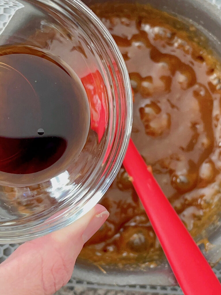 Vanilla added to peanut butter syrup in a saucepan.