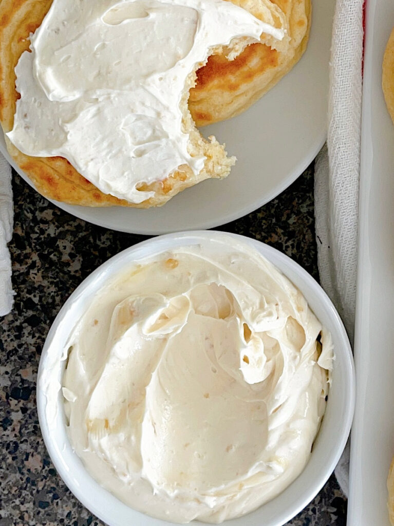 A bowl of whipped honey butter and two drop scones.