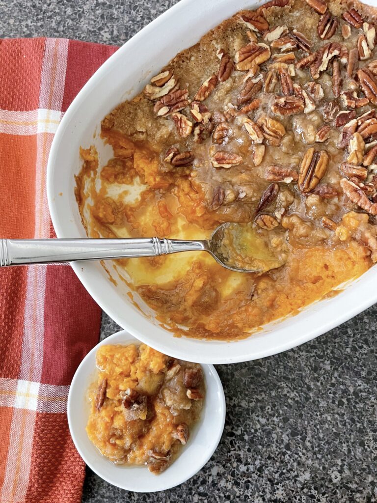 Candied Yams in a baking dish with a spoon next to a plate of candied yams.