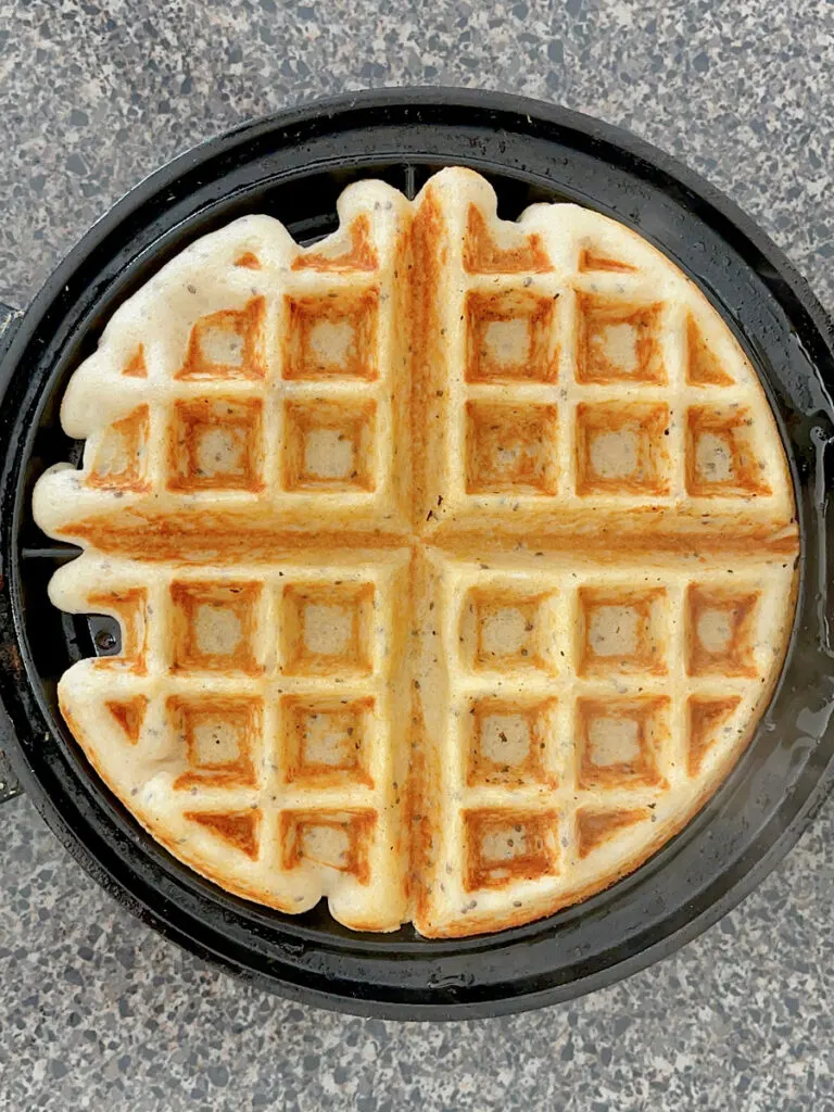 A golden waffle in a waffle iron.