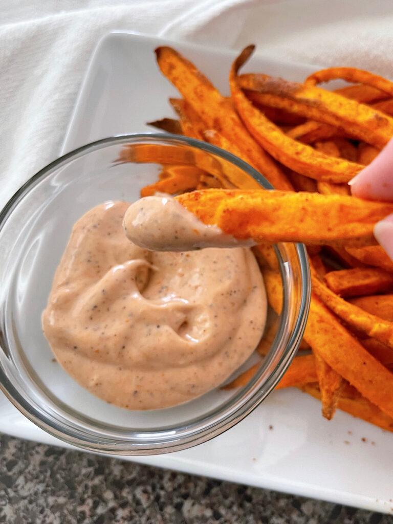 Sweet potato fries on a white plate with fry sauce.