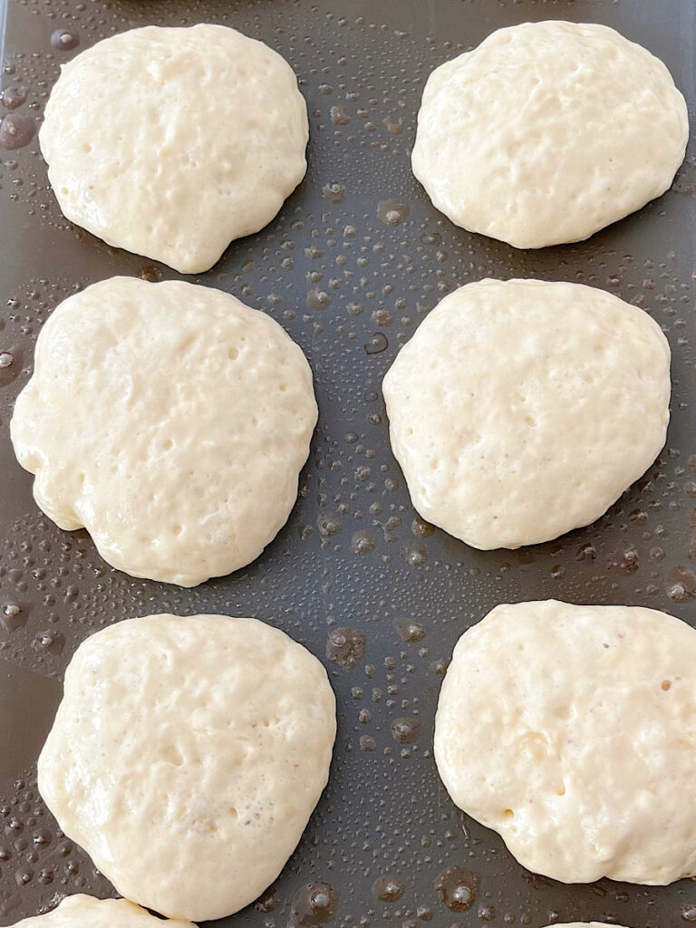 Drop scones cooking on a hot griddle.