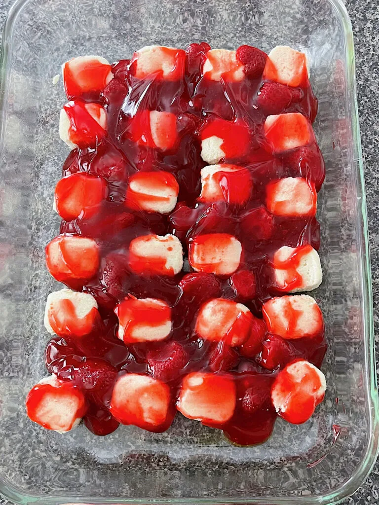 Sugar cookie dough in a baking dish with strawberry pie filling.