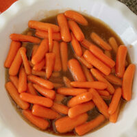 Brown sugar glazed carrots in a white dish.