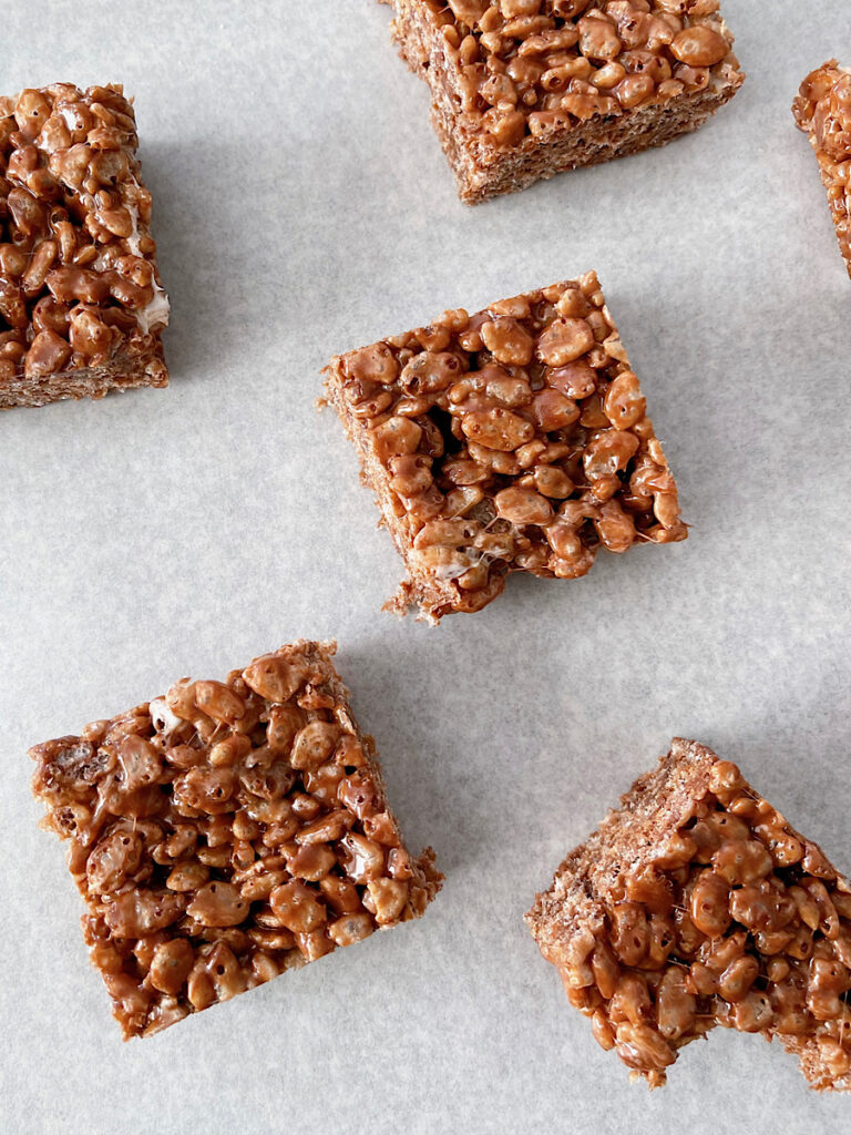 Chocolate rice crispy treat squares on parchment paper.