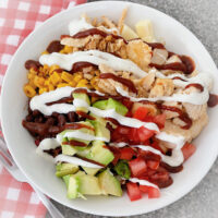 A barbecue chicken salat with a red and white kitchen towel.