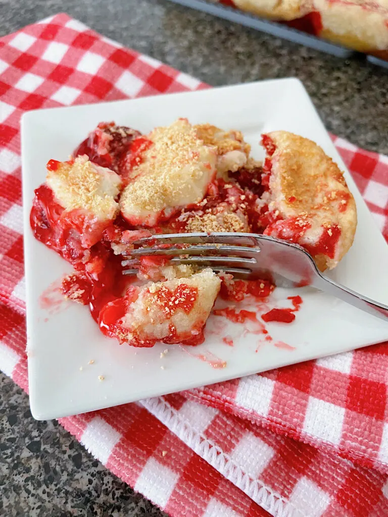 Sugar cookie strawberry dump cake on a white plate with a fork.