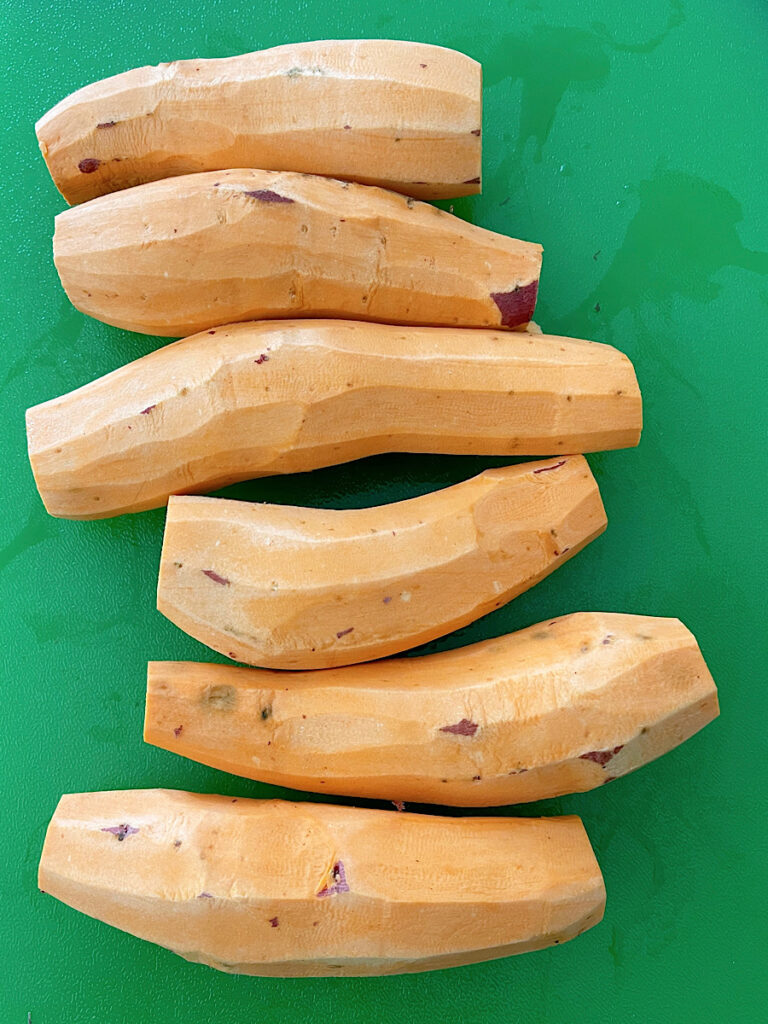 Peeled sweet potato fries on a green cutting board.