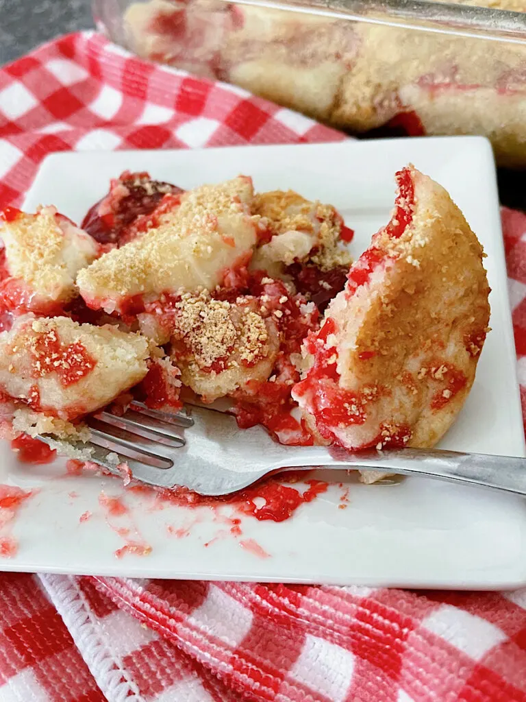 Sugar cookie strawberry dump cake on a white plate with a fork.