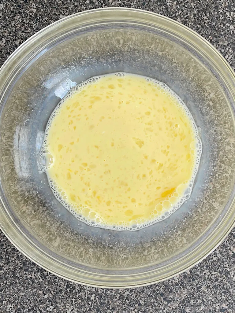 Eggs, sugar, butter, and milk mixed together in a mixing bowl.