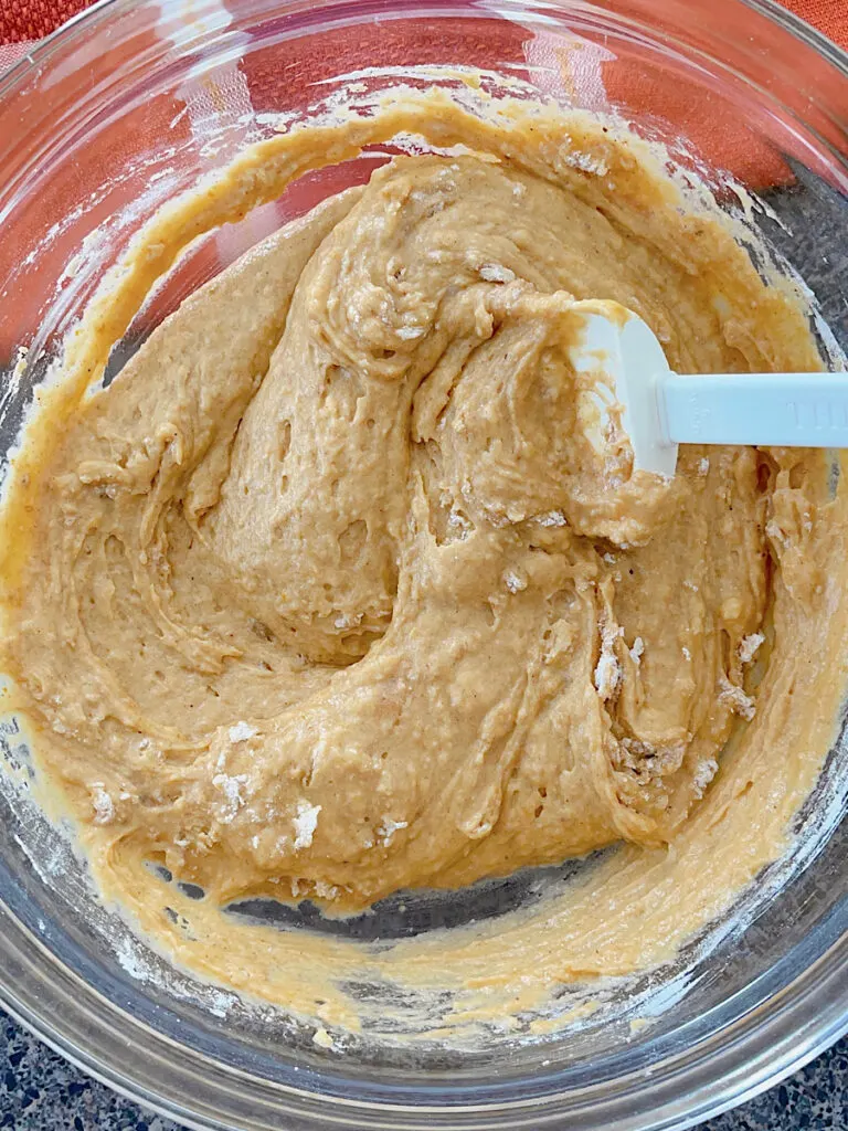 Pumpkin muffin batter in a bowl with a spoon.