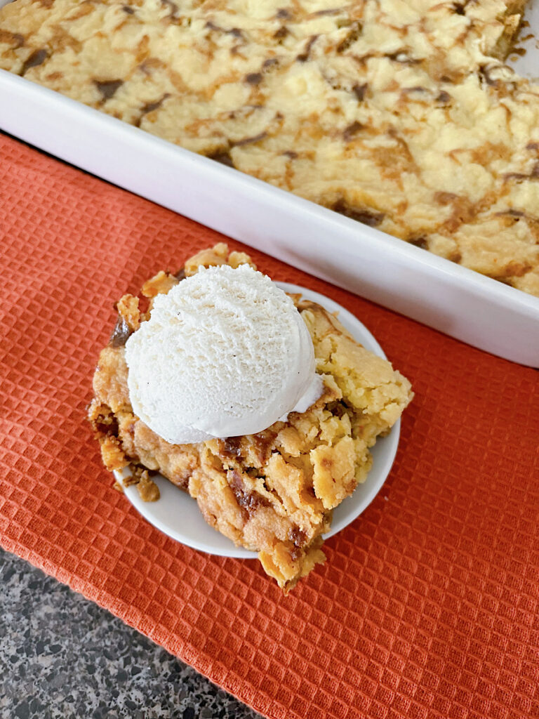 A slice of pumpkin cobbler with a scoop of vanilla ice cream.