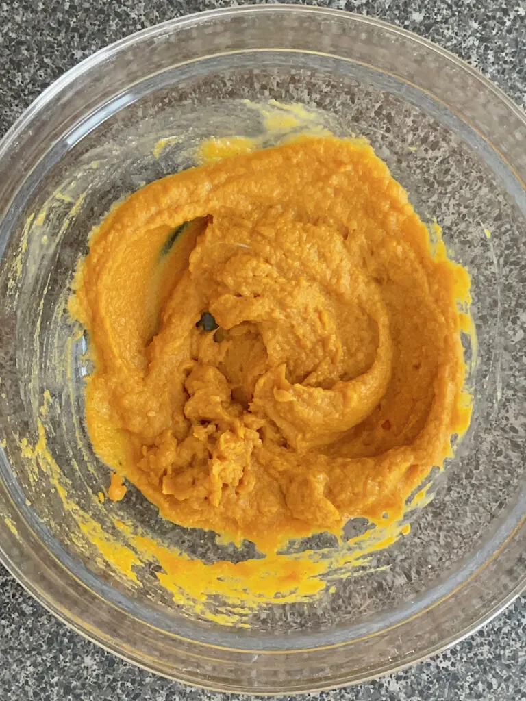 We ingredients for pumpkin cookies in a glass bowl.