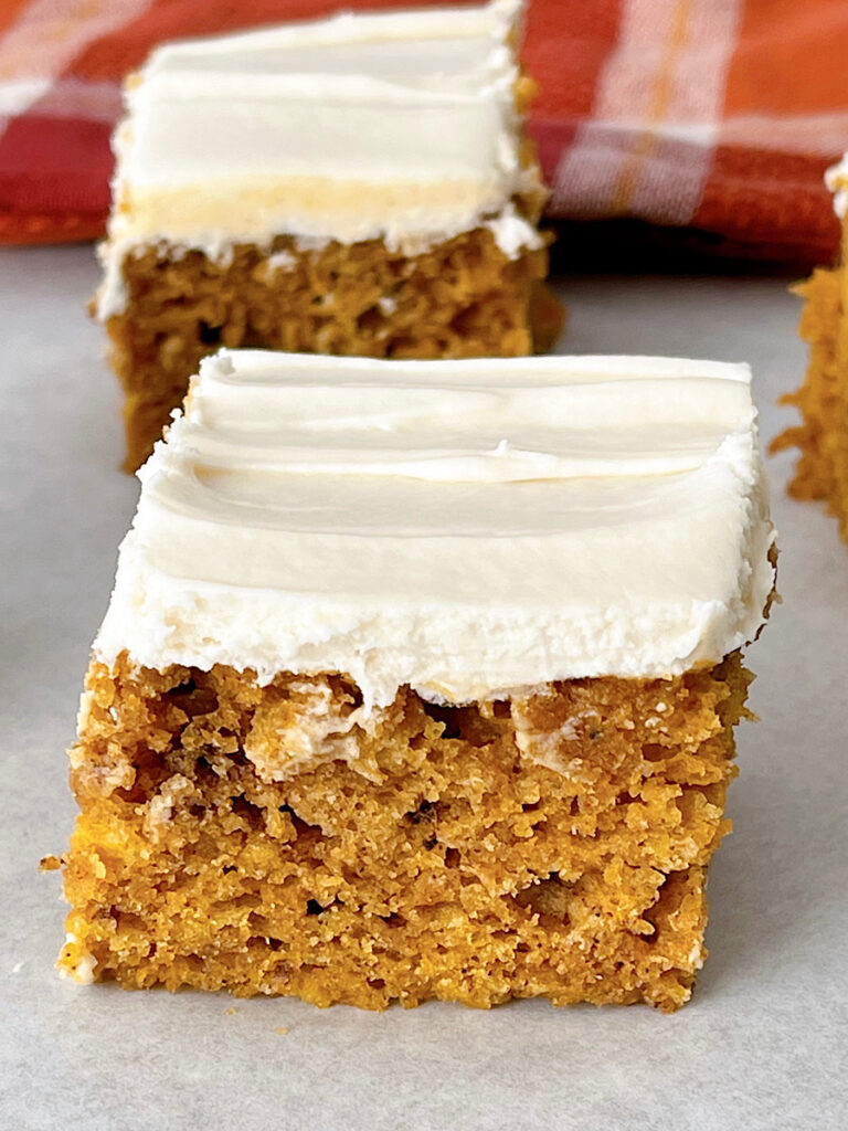 A pumpkin bar square topped with cream cheese frosting.