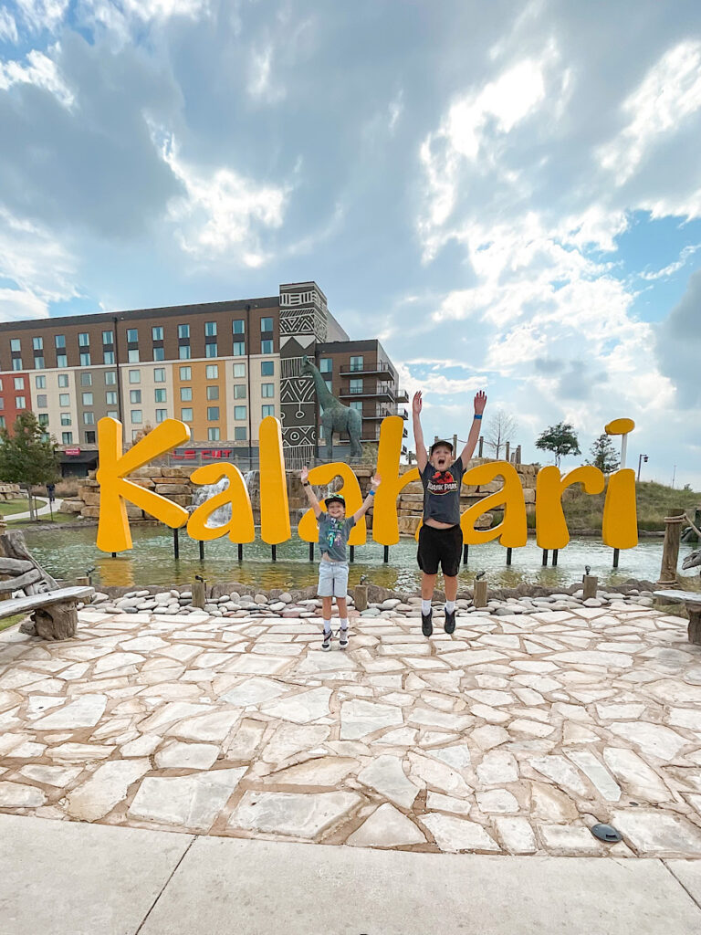 Two kids in front of the Kalahari sign in Texas.